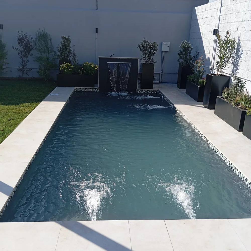 Piscina rectangular con cascada en un patio